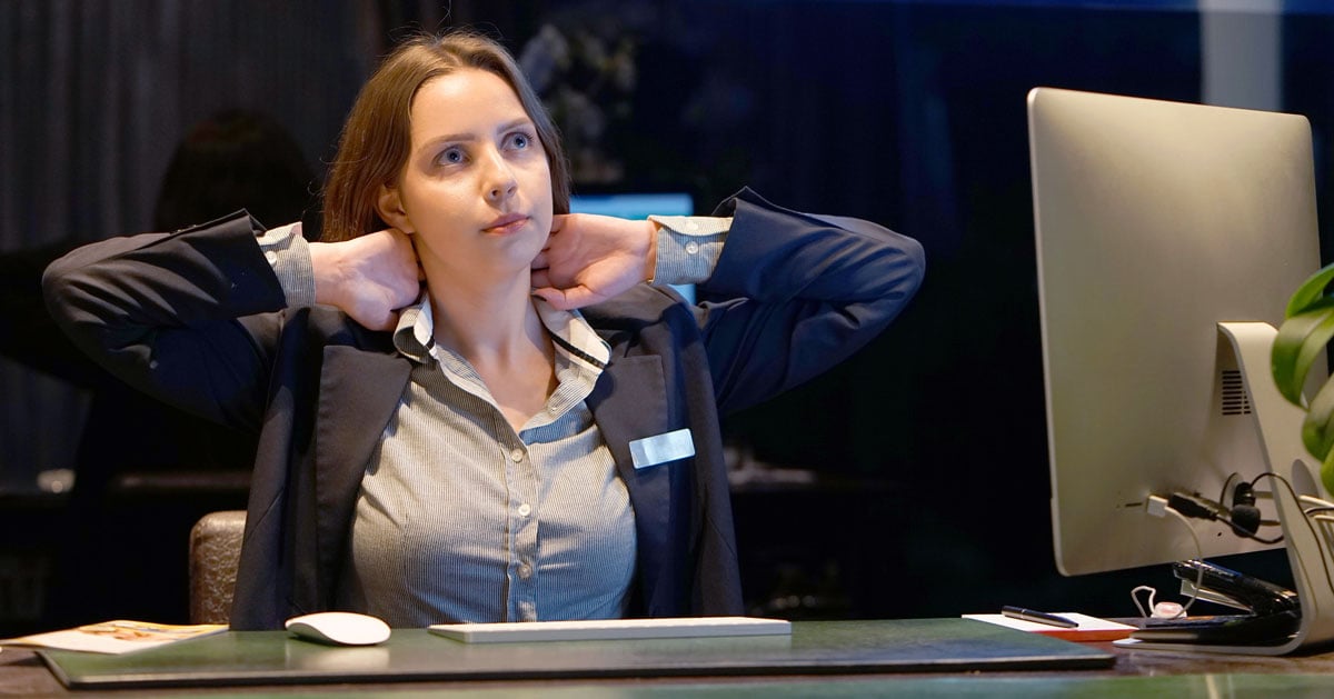 A hotel manager at her desk experiencing neck tension. 