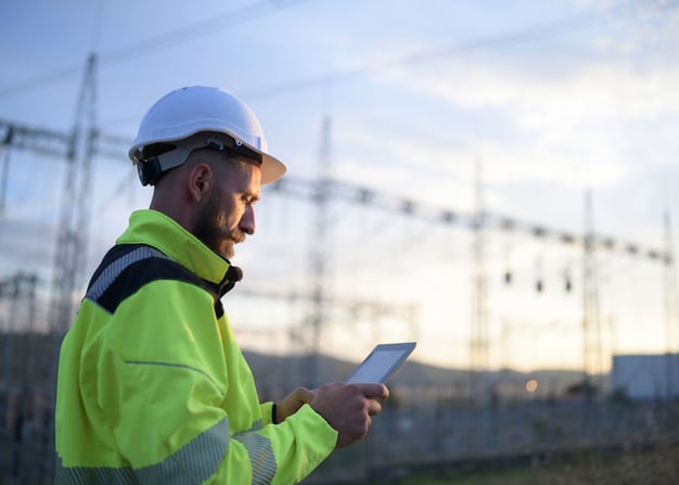 A power plant worker in the field uses a tablet.