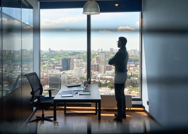 An entrepreneur looks out over a city from his office.