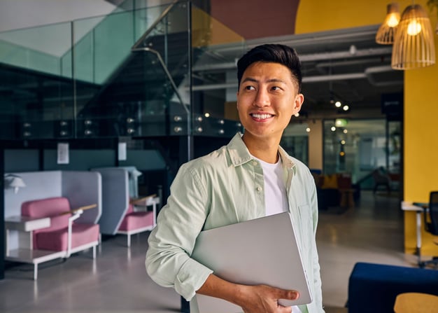 An entrepreneur holding a laptop walks through a shared workspace.