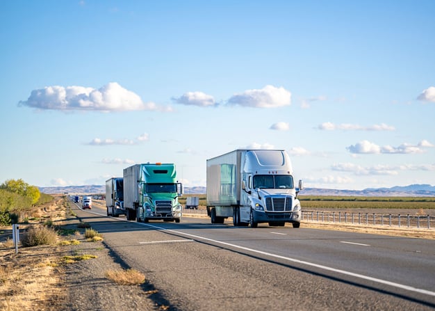 Multiple semis on a rural roadway. 
